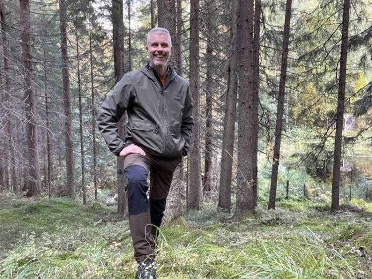 Mies seisoo kumisaappaat jalassa metsän keskellä